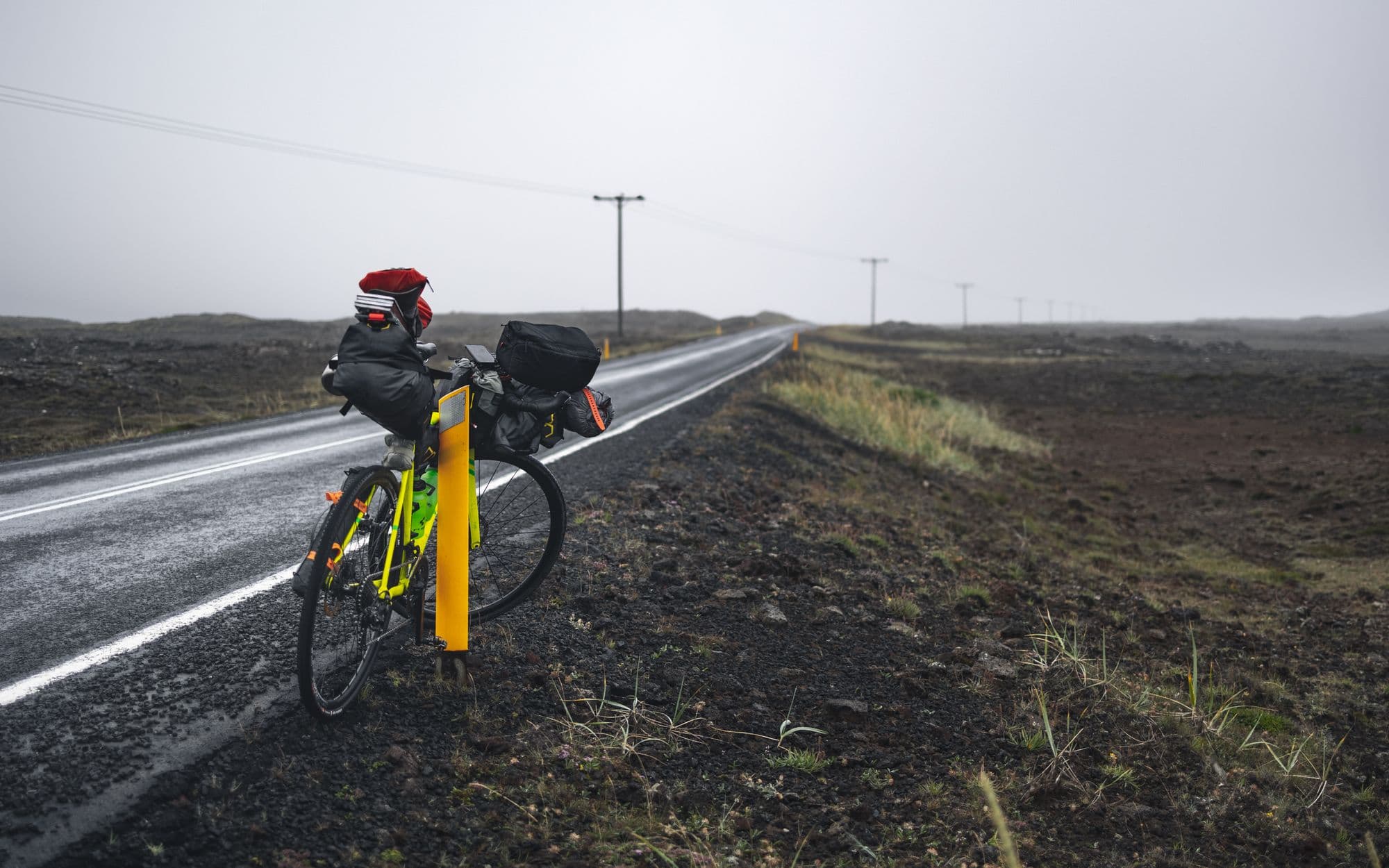 Vélo chargé de sacoches arrêté au bord d'une route déserte dans la brume